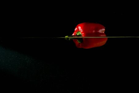 Fresh paprika floats on water isolated on black. Vegetable.