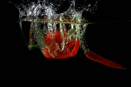 Red fresh paprika and chili pepper splash in water on a black background. Spicy and sweet tastes....