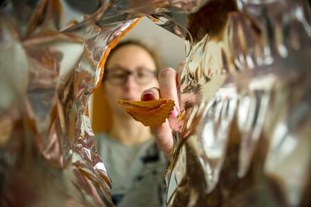 Woman takes chips from the package, photo from the package. Fast food.