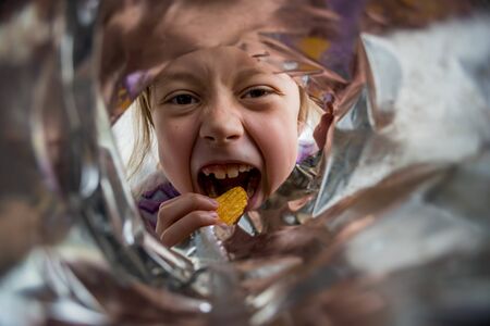 A child takes chips from the package, a photo from the package. Fast food.の写真素材