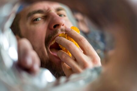 A bearded man takes chips from the package, photo from the package. Fast food.の写真素材
