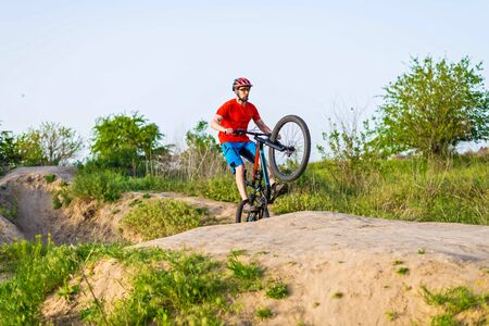 Extreme cycling concept, cyclist jumping on a mountain bike. Cyclist in a bright orange t-shirt and helmet.の写真素材