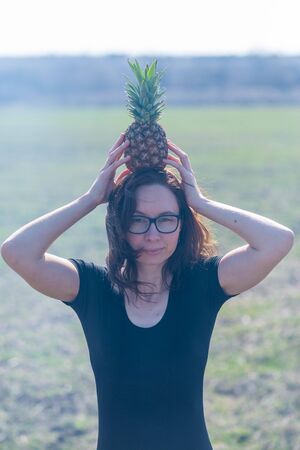 Young woman holds pineapple outdoors. Woman with pineapple.