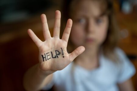 Little girl asks for help, help written on hand. Domestic and child abuse. Protecting the rights of the child.の写真素材