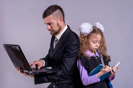 Back to school concept. A schoolgirl is holding a book, and dad is a laptop. The concept of distance education.の写真素材