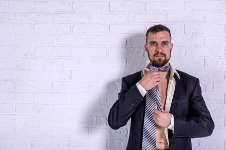 A bearded man is tying a tie. Portrait of a man.