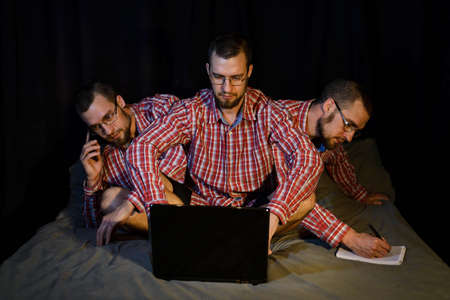 Remote work. The freelancer sits on the bed and multitasks at the same time. Freelance.の写真素材