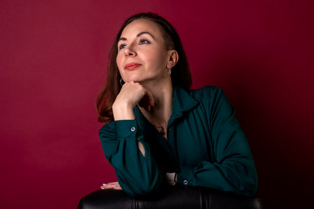 Business photo session of a young woman in an emerald shirt on a red background. Stylish woman.の写真素材