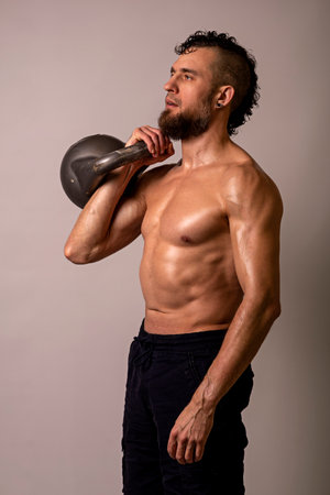 Young muscular man posing with a kettlebell on a light background. Sports lifestyle.の写真素材