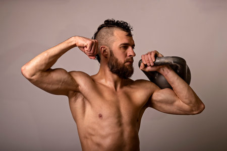 Young muscular man posing with a kettlebell on a light background. Sports lifestyle.の写真素材