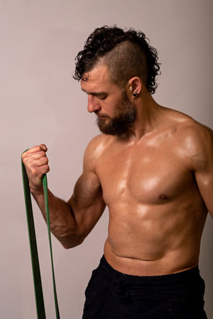 Young muscular man posing with sports tires on a light background. Sports lifestyle.の写真素材
