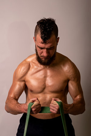 Young muscular man posing with sports tires on a light background. Sports lifestyle.