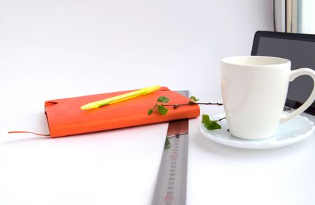 Notebook, ruler, twigs with green leaves with a pen, coffee mugs, tablet on a white background, close-upの写真素材
