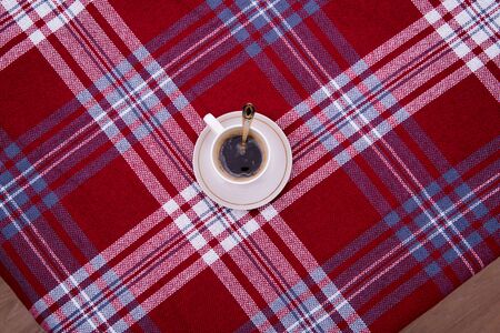 Coffee mug on the table, red and white tableclothの写真素材