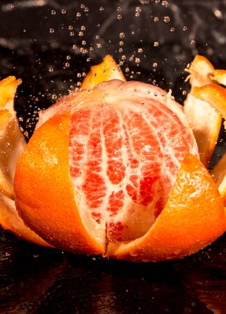 grapefruit, peeled slices, drops of water on a black backgroundの写真素材