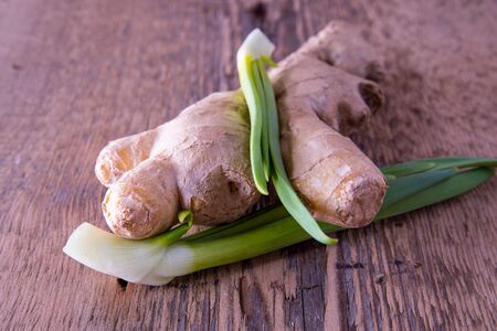 Green onion, ginger on a wooden background