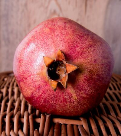Pomegranate on wicker from wooden substrateの写真素材