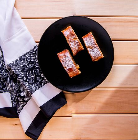 Apple strudel on a black plate with a white napkin on a wooden table, close-up, top viewの写真素材
