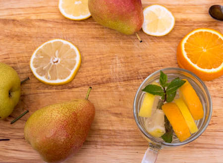 Two glasses and a bottle with drinks from fruits, fruits pear, pelesin, lemon lie on a cutting board