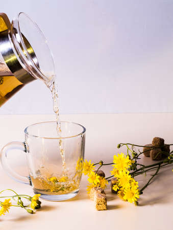 Carafe of snapitcomi and a glass of drink, yellow daisies, on the tableの写真素材