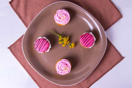 Several colorfully decorated cupcakes on a brown plate, side view