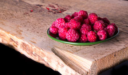Raspberries on a plate and a wooden tableの写真素材