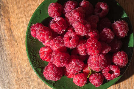 Raspberries on a plate and a wooden table
