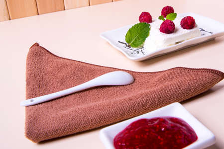 A plate of ice cream with raspberry jam on the tableの写真素材