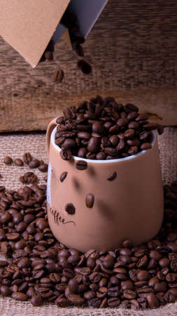 Coffee beans fall from the bag into the mugの写真素材