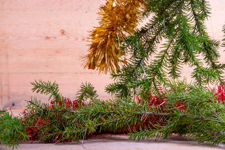 Fir branches with tinsel on a light wooden background.Christmas card.Still-lifeの写真素材