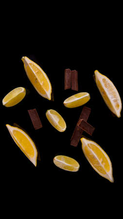 Slices and slices of lime lemon with chocolate pieces on a black background close upの写真素材