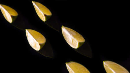 Slices and slices of lime lemon on a black background close upの写真素材