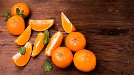 Tangerines whole slices of mint leaves on a cutting Board, old dark wooden table, close-up with space for textの写真素材