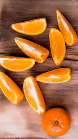 Whole tangerines, slices on a cutting Board, old dark wooden table, close-up with space for texの写真素材