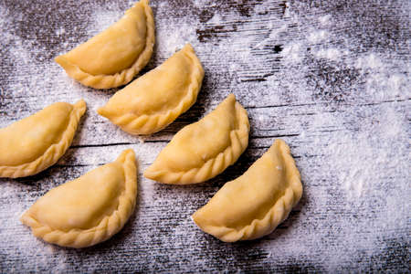 Homemade dumplings, vareniki on an old wooden table, sprinkled with flour, space for textの写真素材
