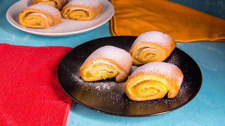 Baking strudel, cake on a black and white plate on a bluish background with a yellow napkin, space...