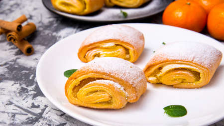 Strudel baking, powdered cake with Mandarin mint leaves, cinnamon sticks on a white, black plate on a black and white background with a space for text, side viewの写真素材