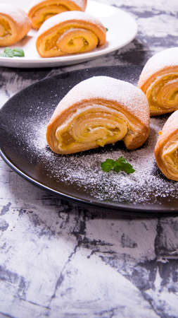 Strudel pastry, a cake powdered with mint leaves on a black and white plate on a black and white...