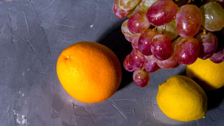 Bunch of grapes, lemon, orange on black and white background, close - up, with space for text, background, postcard, Wallpaper,の写真素材