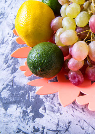Bunch of grapes, lemon, orange, lime in a vase on a black and white background, close-up, with space...