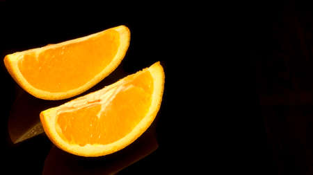 Orange slices on a black background with reflection, background, postcard, advertisingの写真素材