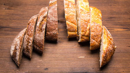 Sliced rye, white bread on an old wooden table, close-up