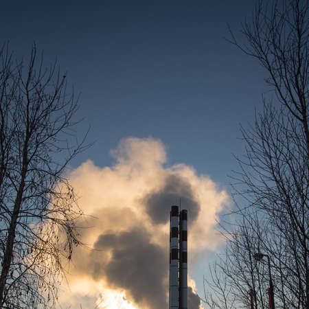 Boiler pipes with smoke against the blue sky, winter, close-upの写真素材