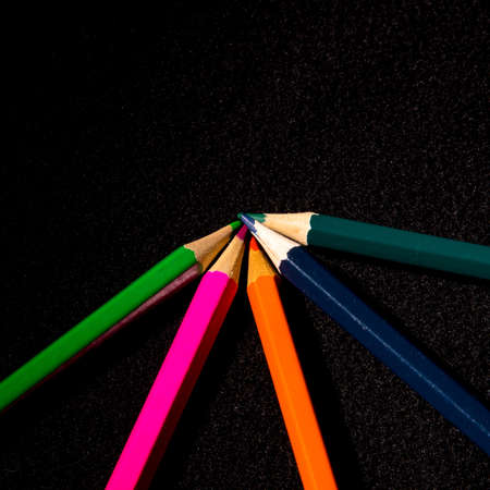 Colored pencils on a black background, close-up, space for text,