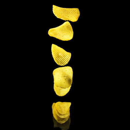 Potato chips fall on the table in a stack on a black background, copy space, levitationの写真素材