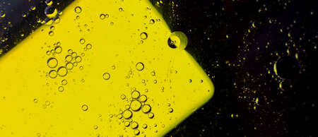Oil bubbles on the water surface in motion, on a yellow background, macro, splash screen, template, copy spaceの写真素材