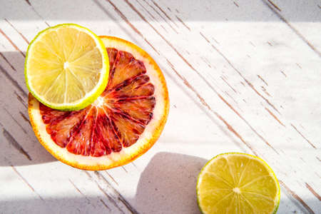 Red orange half, two lime halves close-up, copy space, pattern, rough shadowsの写真素材