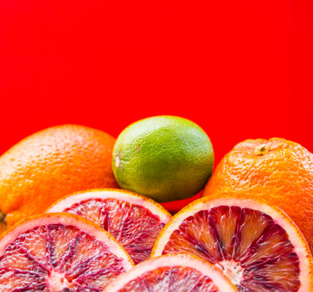 Red orange lime sliced and whole, on red background, close-up, copy space, template, postcardの写真素材