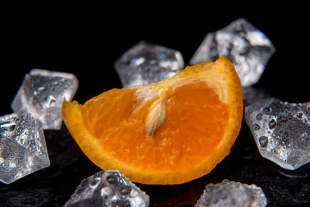 Tangerine slices with ice drops on a black background, close-up, background, template, still lifeの写真素材