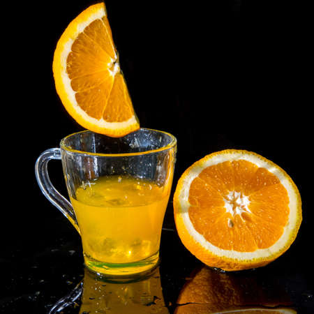 Glass with orange juice and orange halves on a black background, Healthy lifestyle concept, copy space, levitationの写真素材